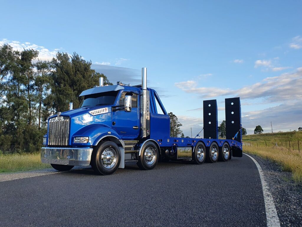 Kenworth T360 beavertail truck photographed outdoors displaying stainless steel accessory components in Sonic Buildings fleet colours.